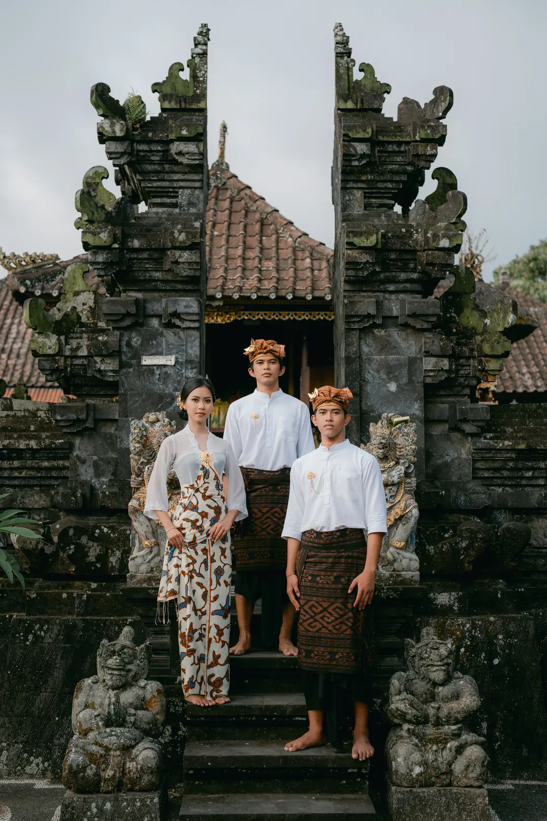 Tiga peserta berdiri bersama di tangga gapura Bali