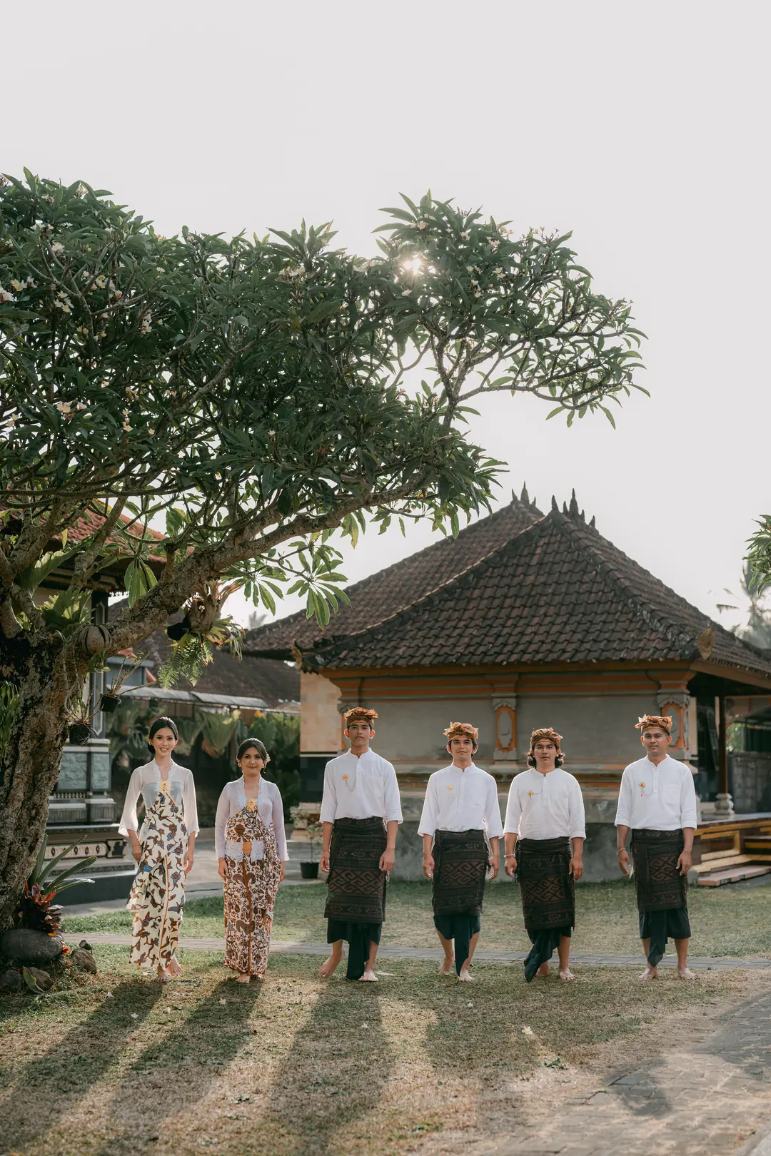 Enam peserta Mepandes di taman di bawah pohon kamboja